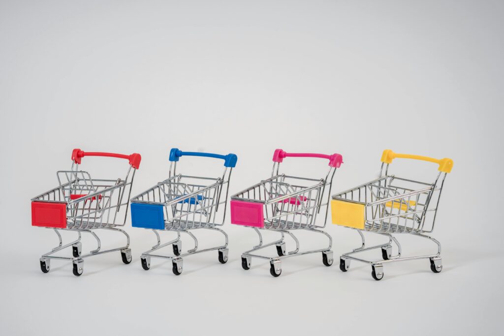 A row of colorful miniature shopping carts arranged against a neutral background.